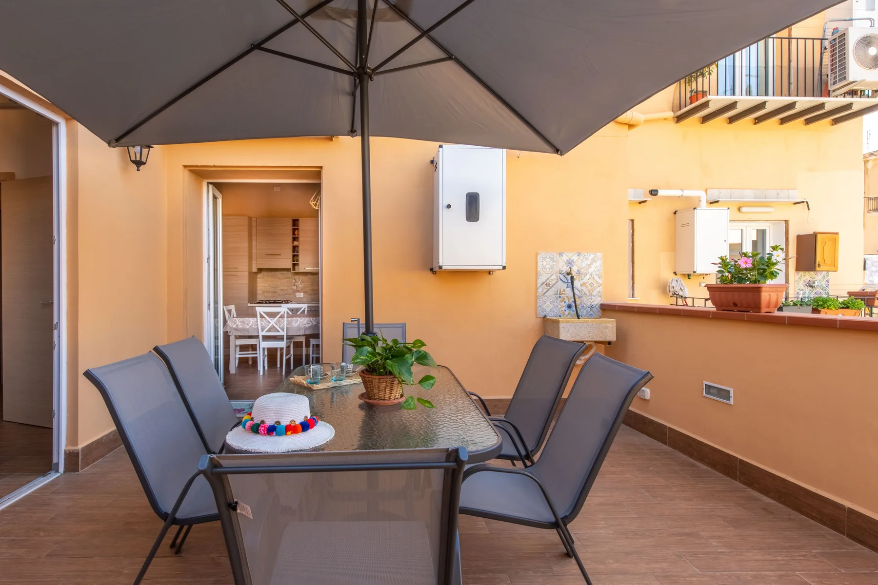 Una zona exterior de comedor a la sombra, con mesa, sillas y una sombrilla grande.