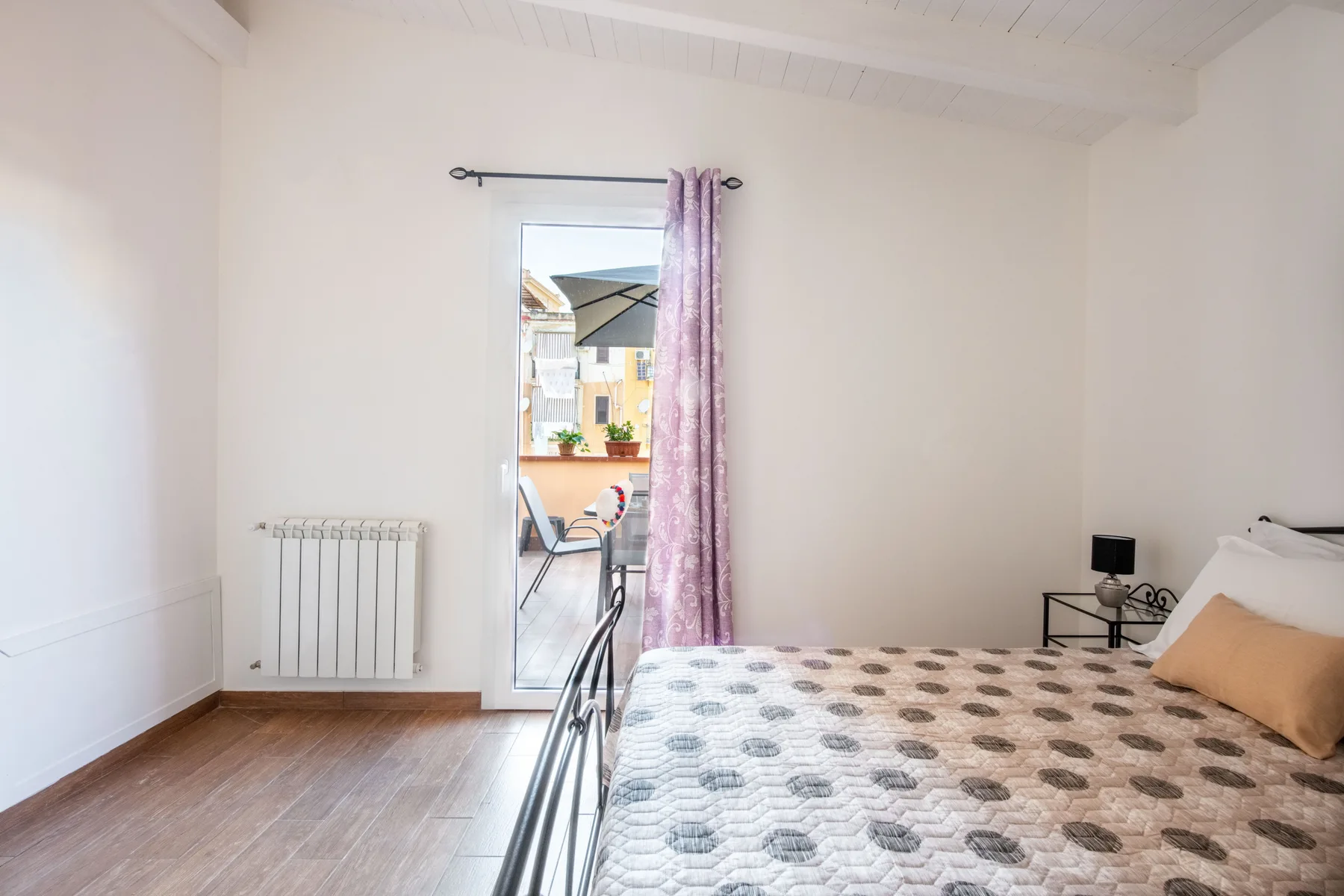 Un dormitorio luminoso con una cama junto a una puerta acristalada alta.