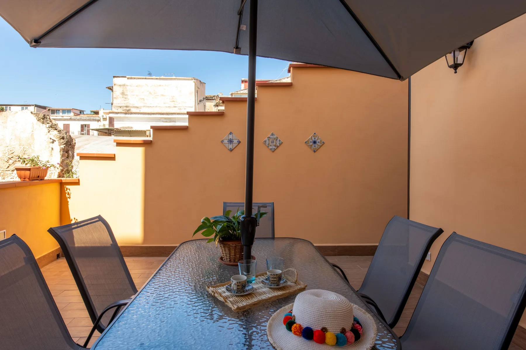 Una terraza soleada con asientos al aire libre y una sombrilla grande.
