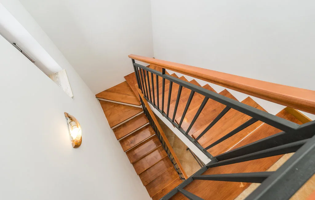 An indoor staircase with wooden steps and a dark metal railing.