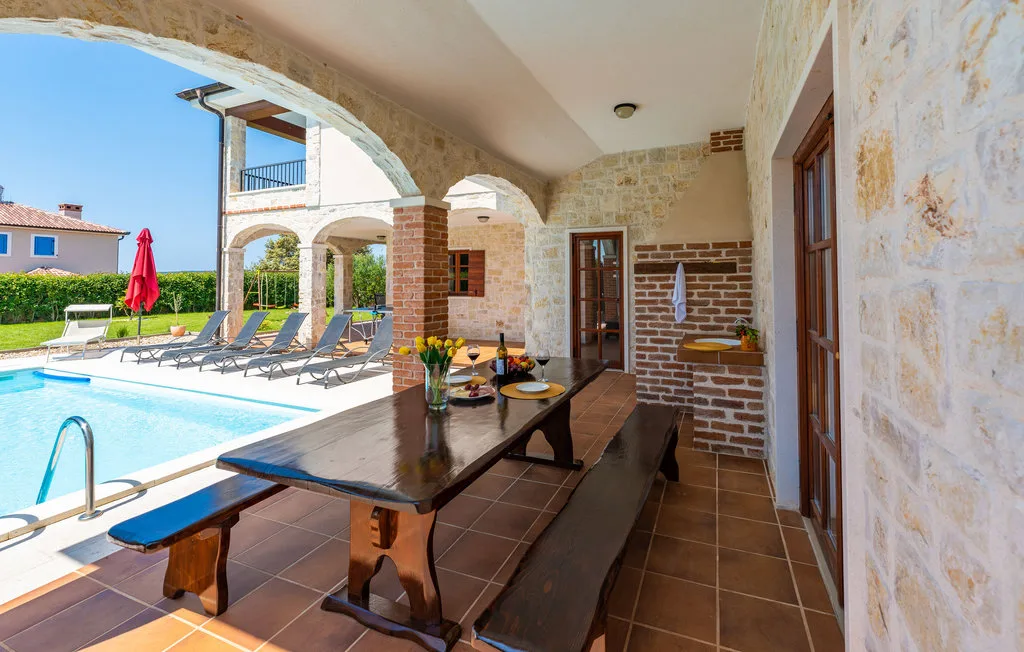 A covered poolside dining area with a long table beside the swimming pool.