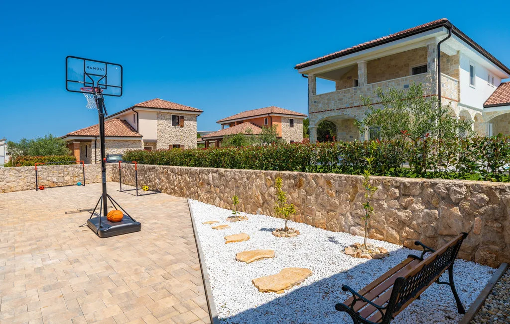 An outdoor basketball court beside a gravel garden and seating area.