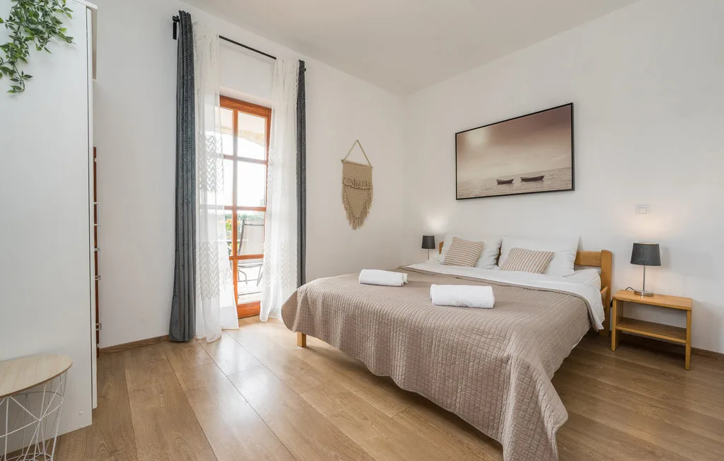 A bright bedroom with a neatly made bed and tall windows.