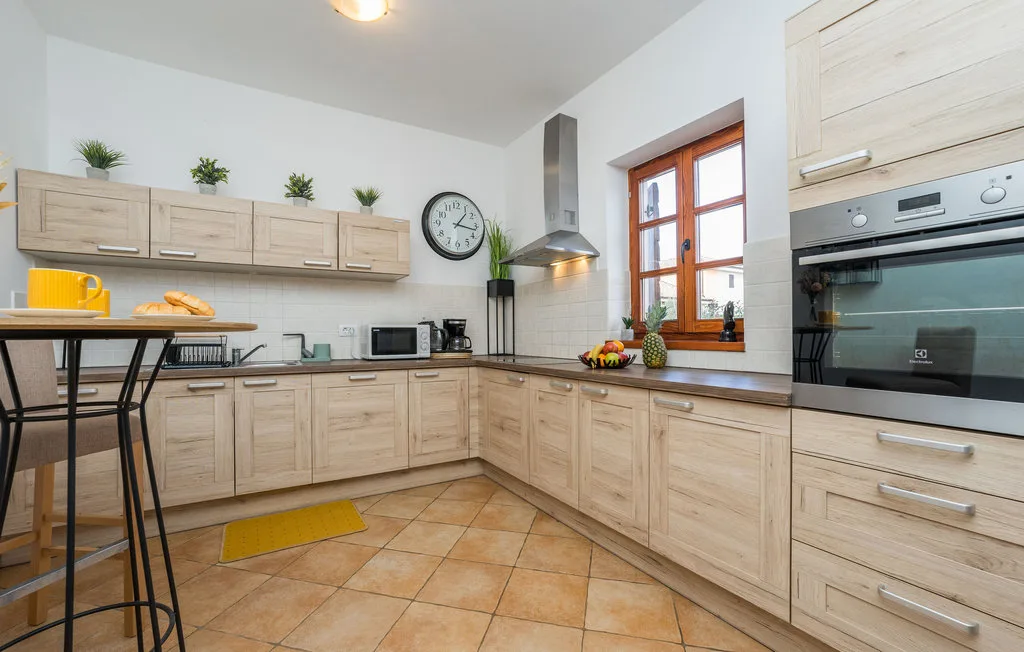 A bright kitchen with light wood cabinets, a countertop, and a dining table.