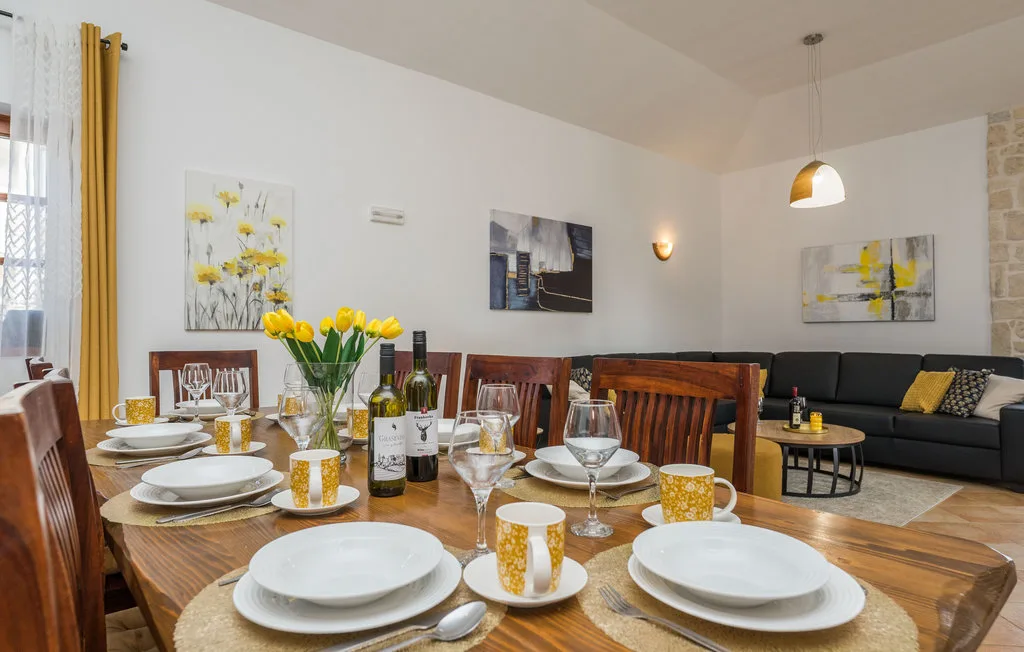 A dining area with a set table and a living room seating area behind it.