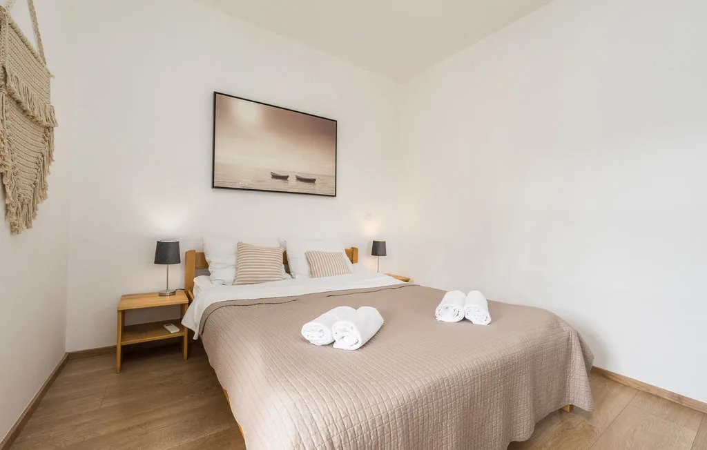 A bedroom with a neatly made bed and framed artwork on the wall.