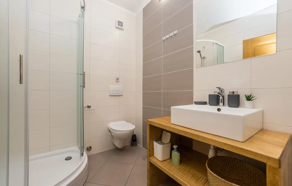 A tiled bathroom with a glass shower and a white vessel sink.