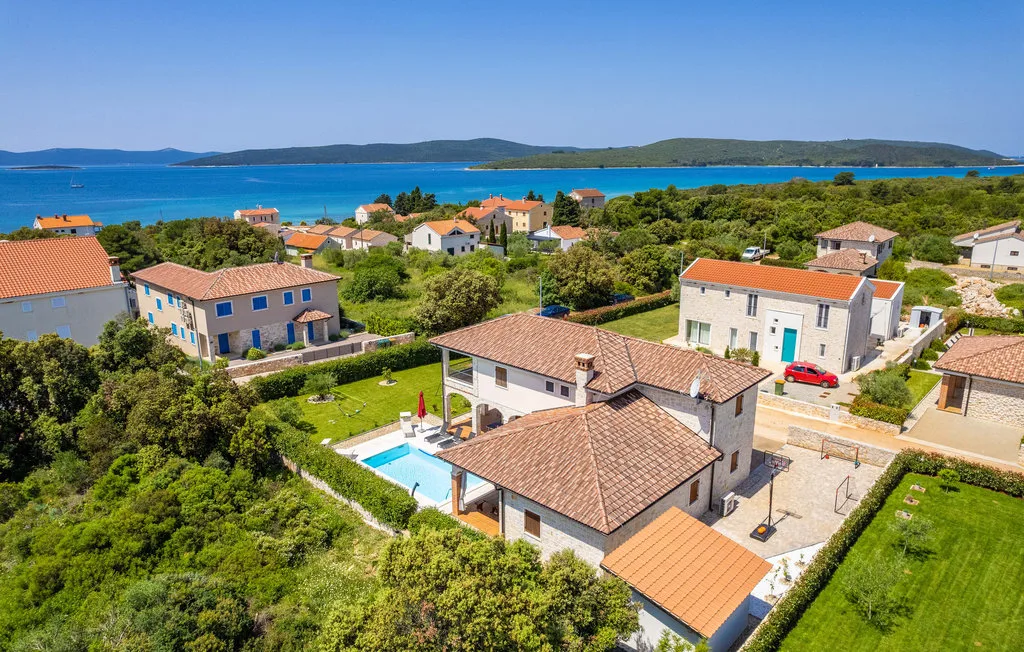 Aerial view of homes among greenery beside the blue sea.