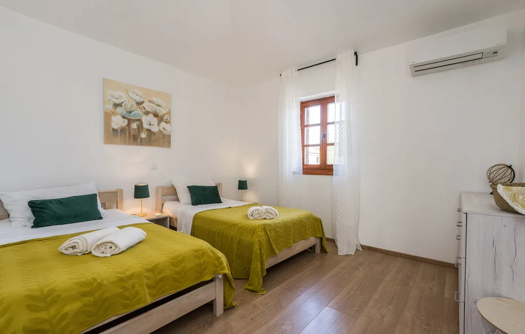 A bright bedroom with two beds dressed in mustard-yellow bedding.