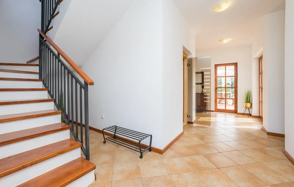 A tiled entry hall with a staircase and a glass-paneled door at the far end.