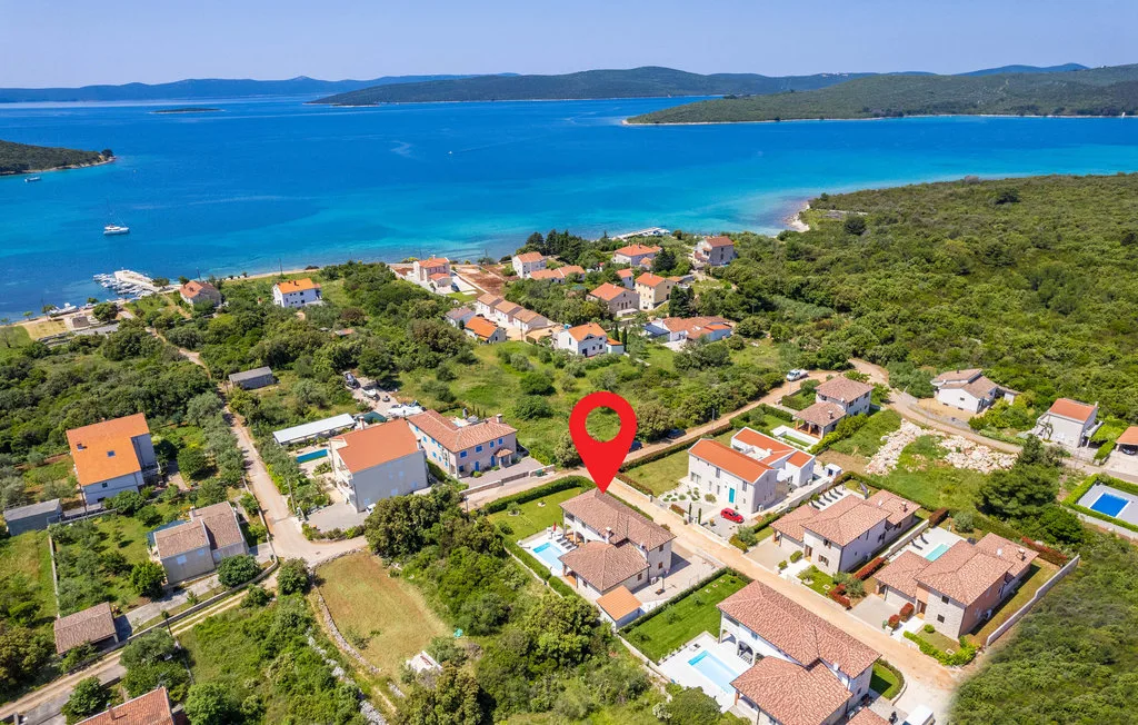 Aerial view of a coastal village with red-roofed houses beside a blue bay.