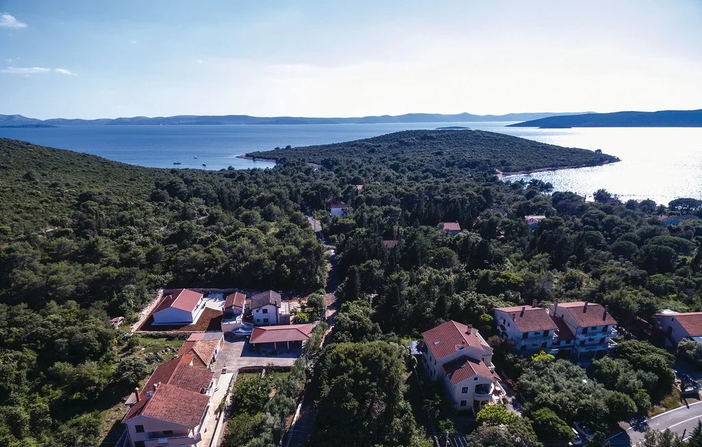 Aerial view of homes among trees beside a bay and wooded peninsula.