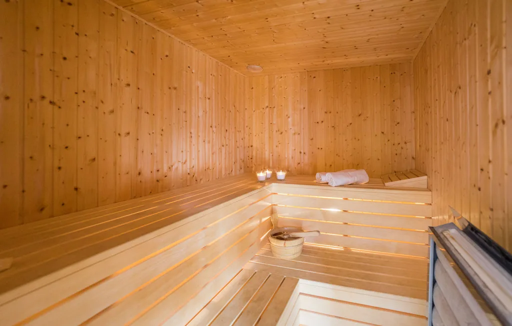 A wood-paneled sauna with tiered benches and a folded towel.