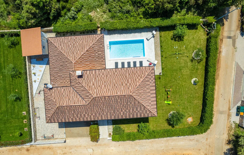 An aerial view of a house with a swimming pool and surrounding lawn.