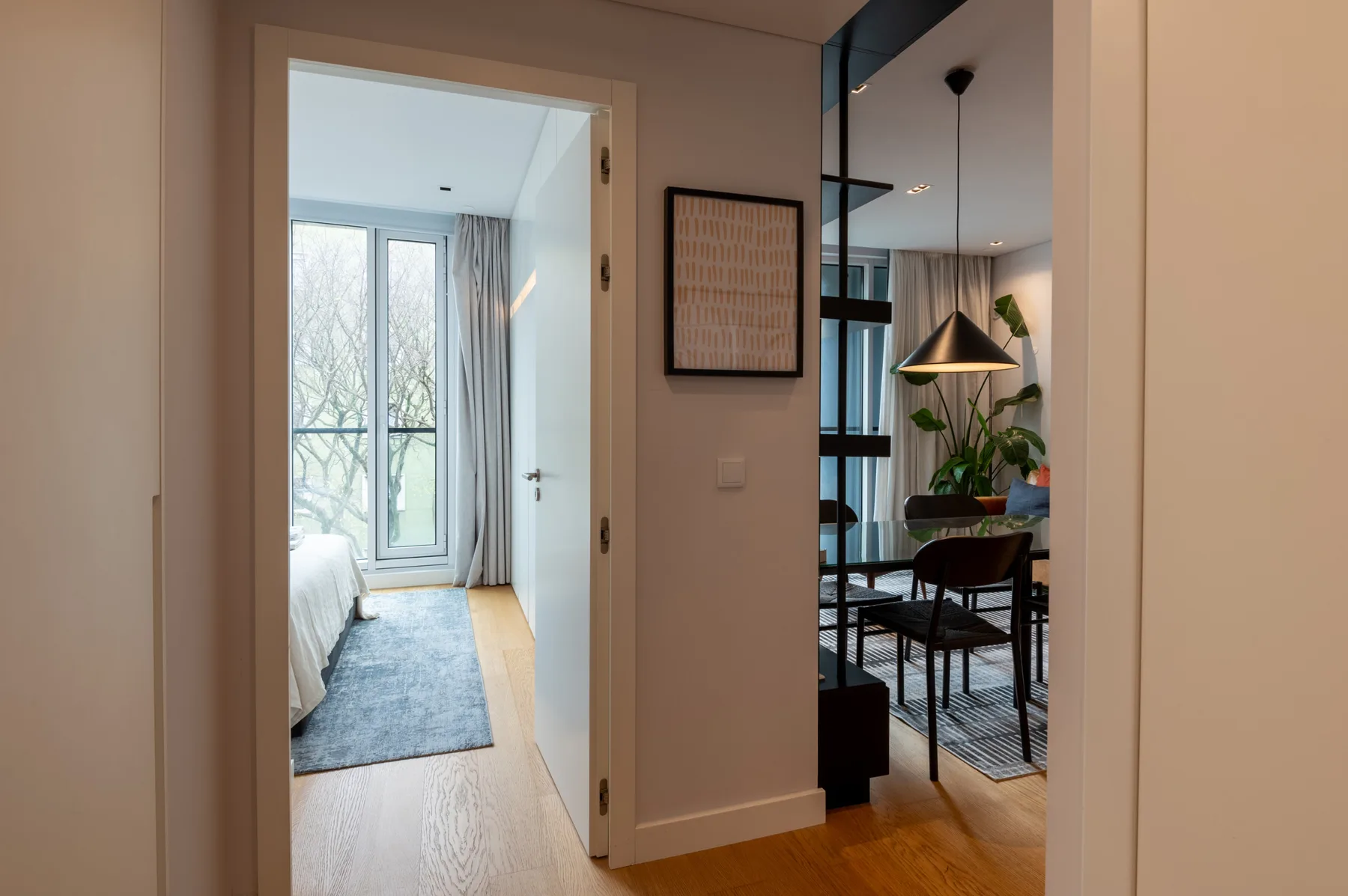 An apartment interior with an open doorway to a bedroom and a dining area.