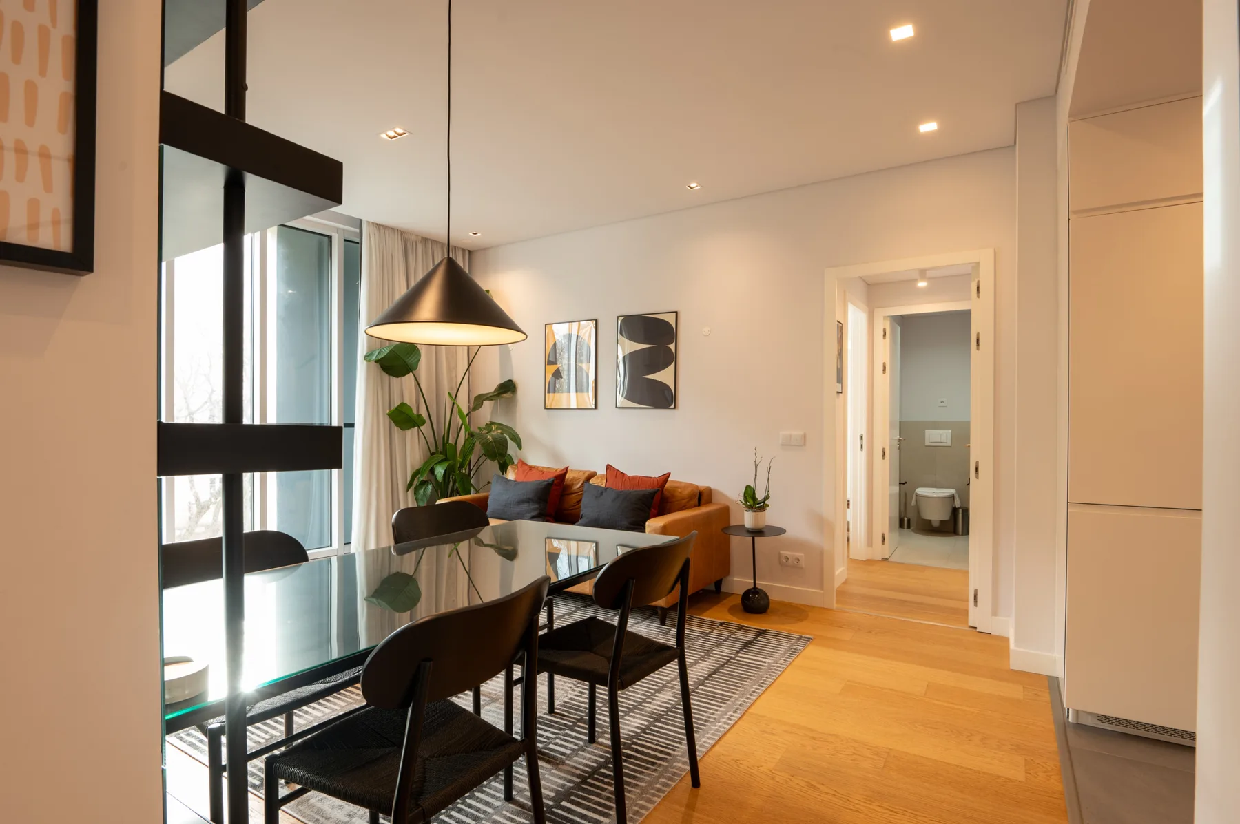 A living and dining area with a table, seating, and an orange sofa.
