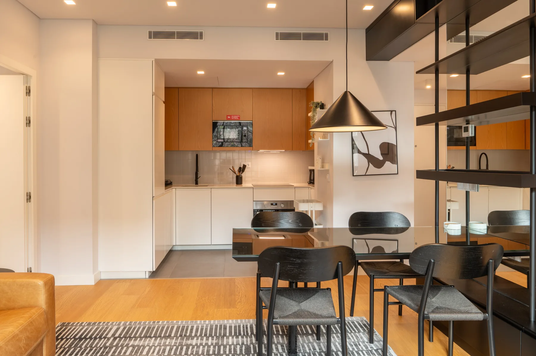 A modern dining area with a kitchen and dark seating.