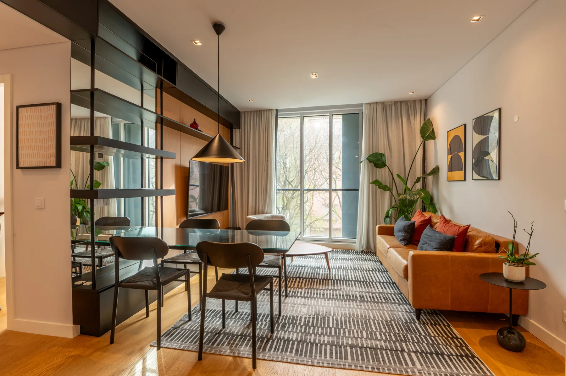 Sala de estar y comedor con mesa, asientos y ventanales.