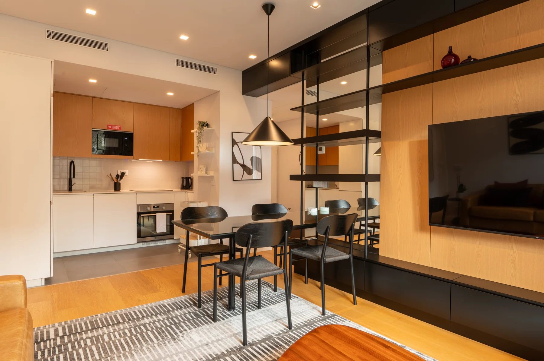 An open-plan kitchen and dining area with a table beside a wall-mounted television.