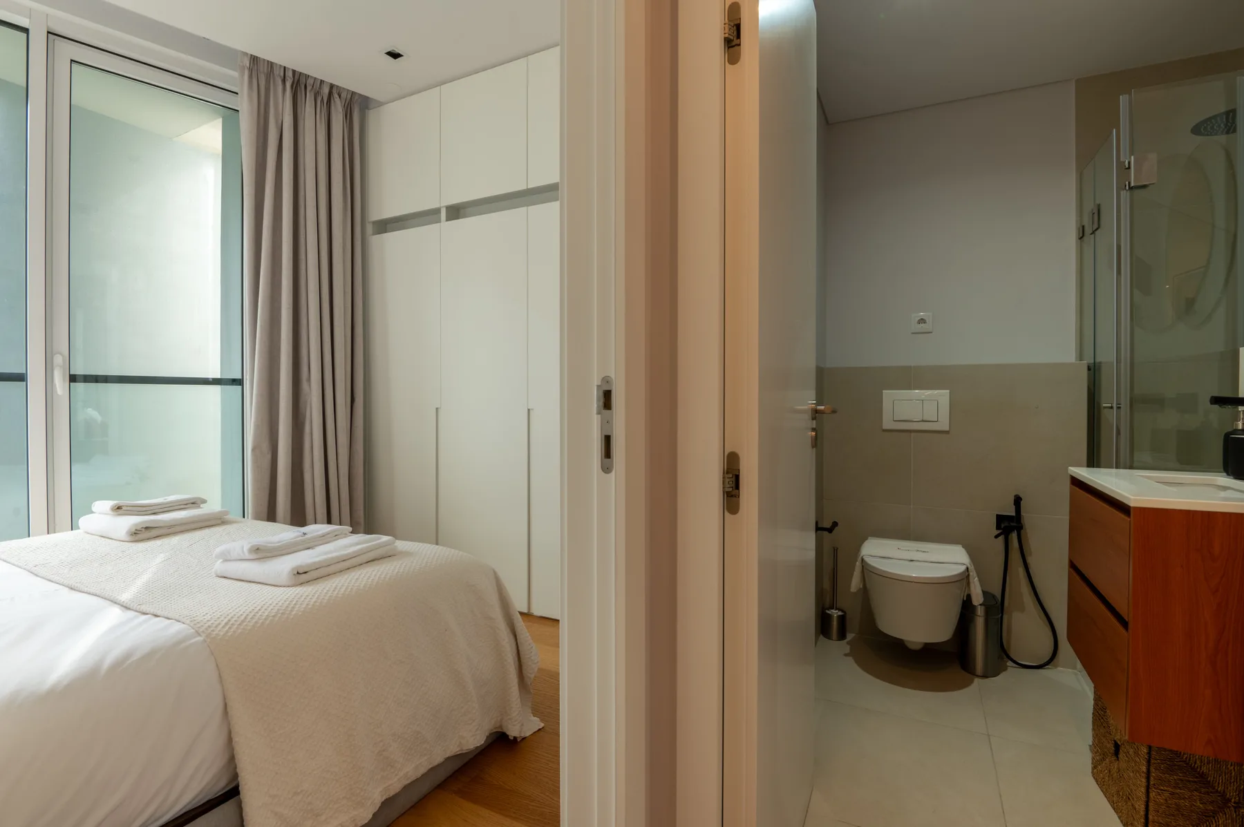 A bedroom with a neatly made bed beside an adjoining bathroom.