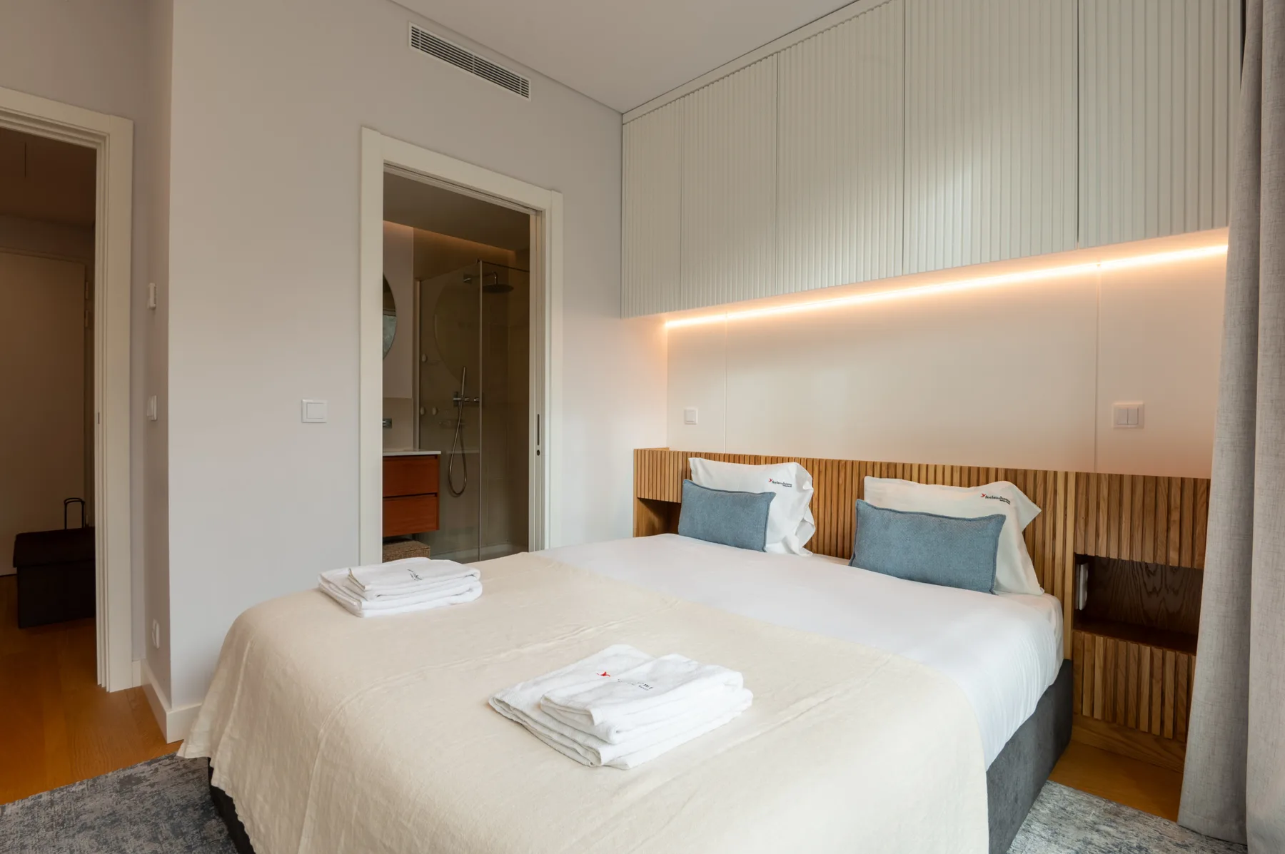 A bright bedroom with a neatly made bed and folded towels.