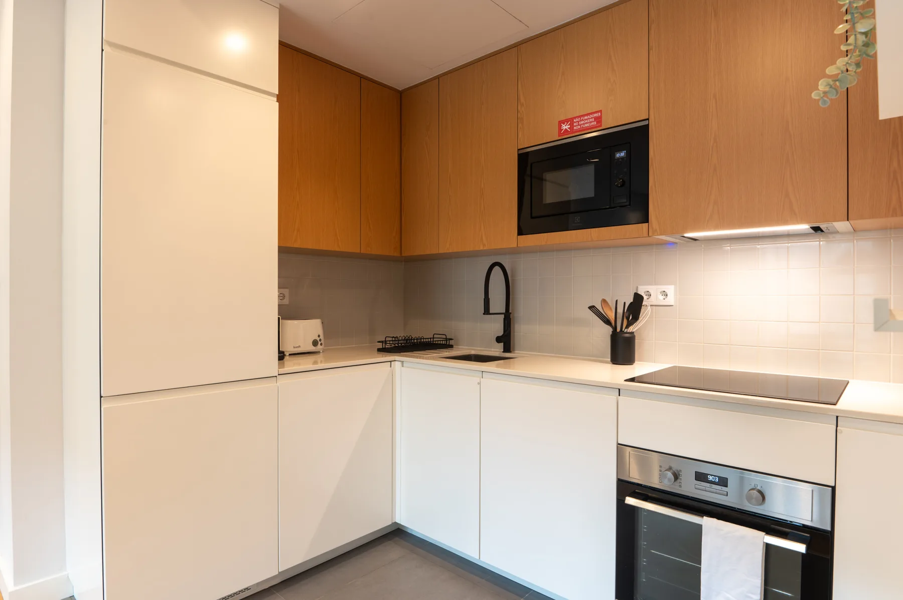 A modern kitchen with wood cabinets, a microwave, and an oven.