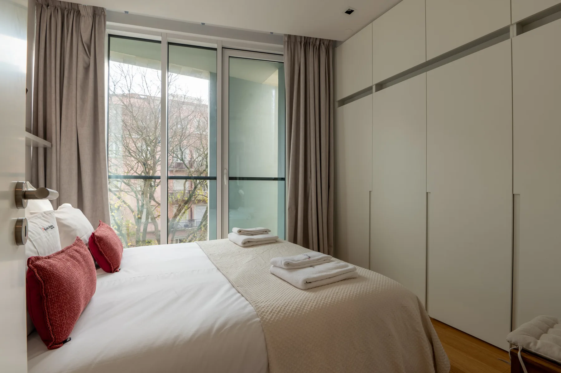 Un dormitorio con una cama vestida de blanco y una ventana grande.