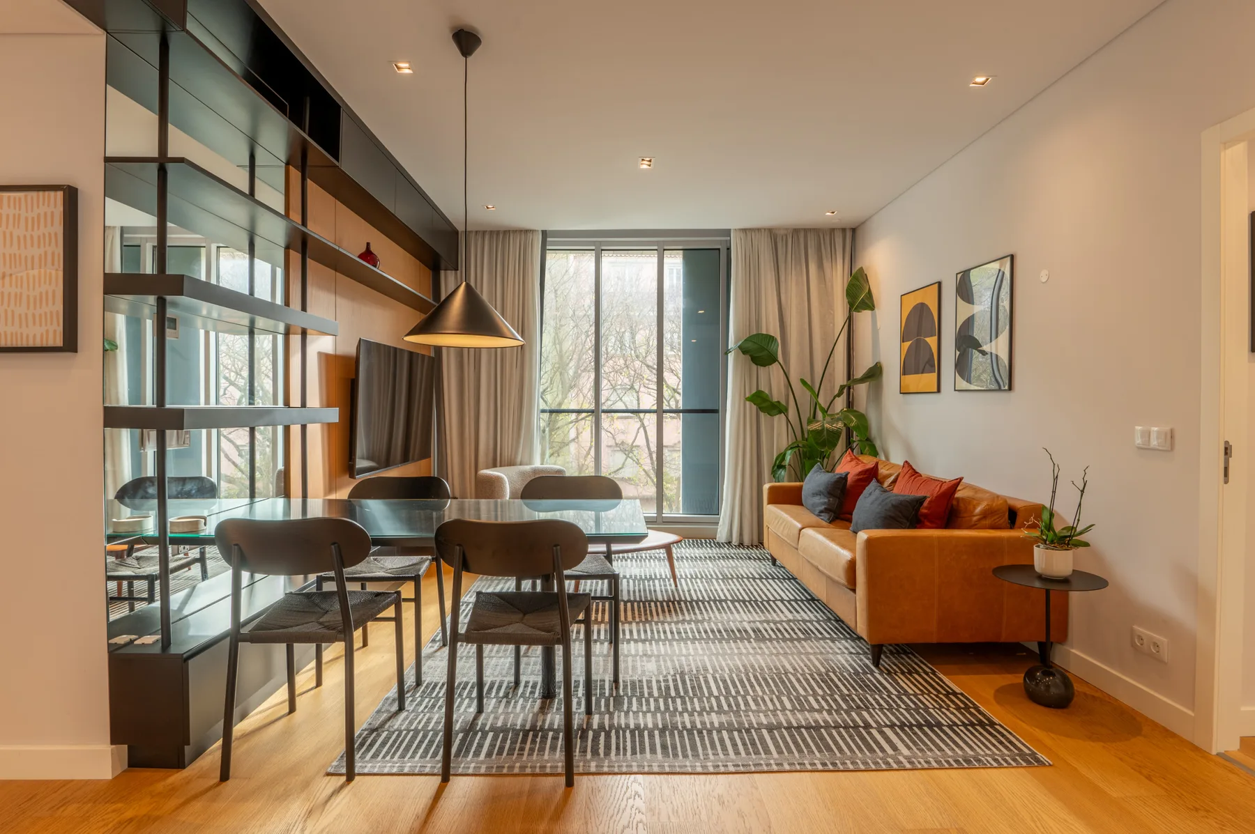 Living room with a dining table, seating, and large windows.