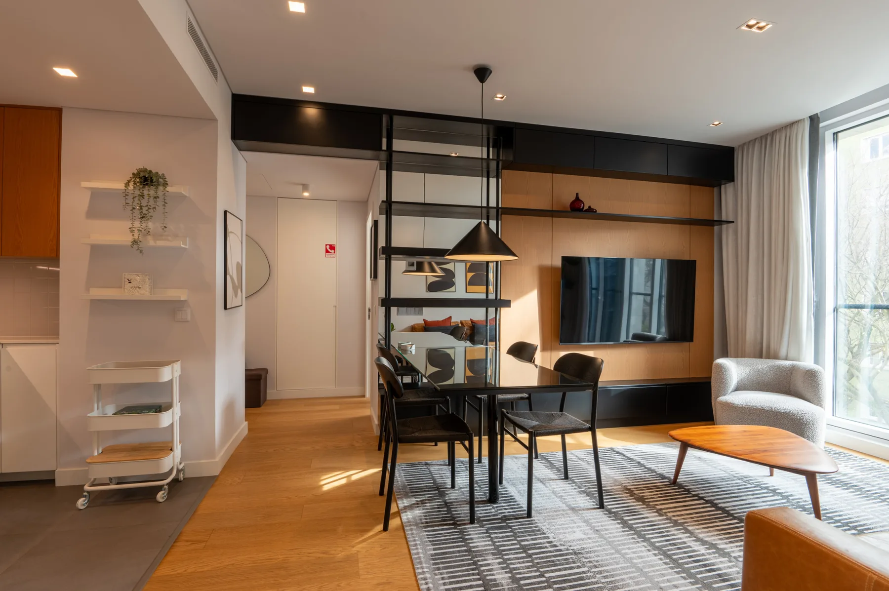 A modern living and dining area with a table, seating, and a wall-mounted television.