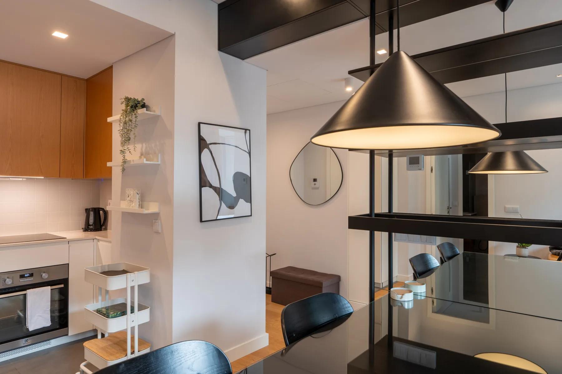 A modern kitchen and dining area with wood cabinetry and a black pendant light.