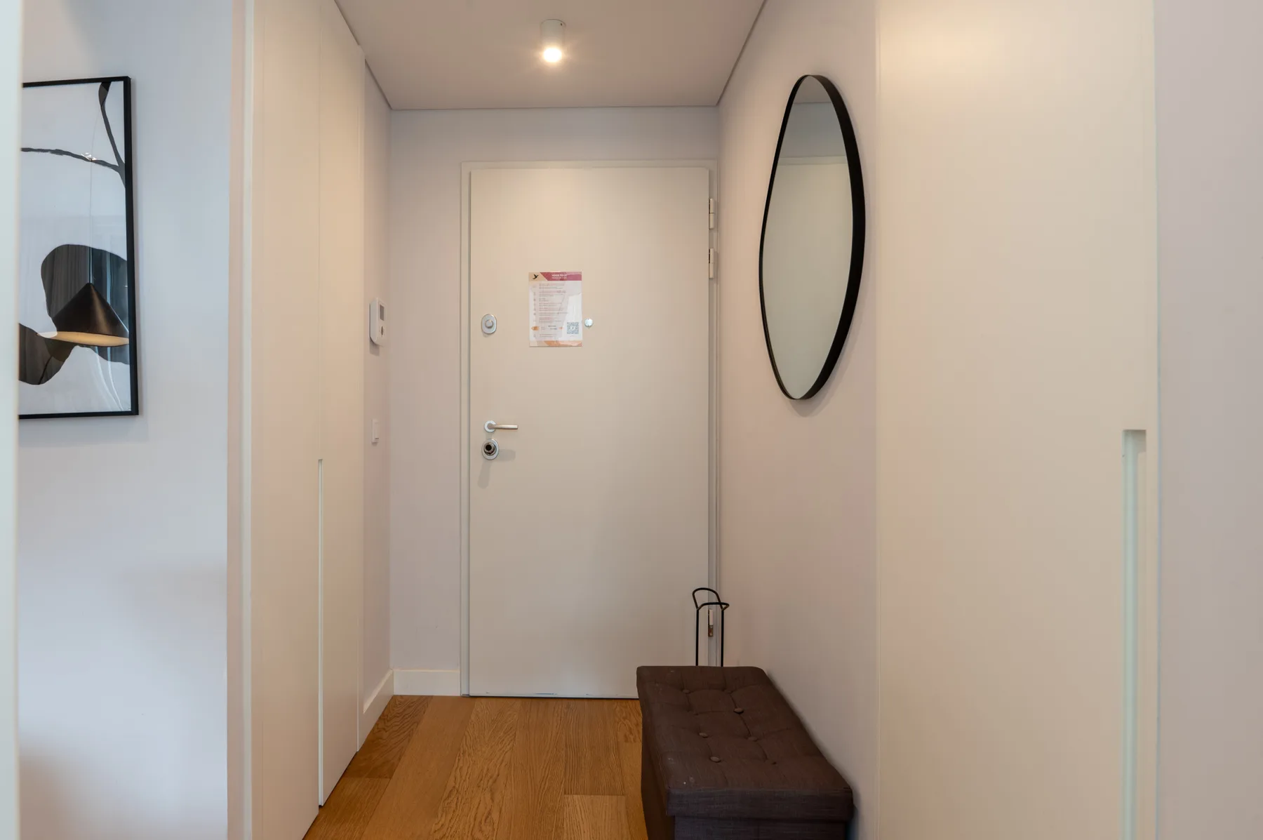 A hallway with a closed door, a bench, and a wall mirror.