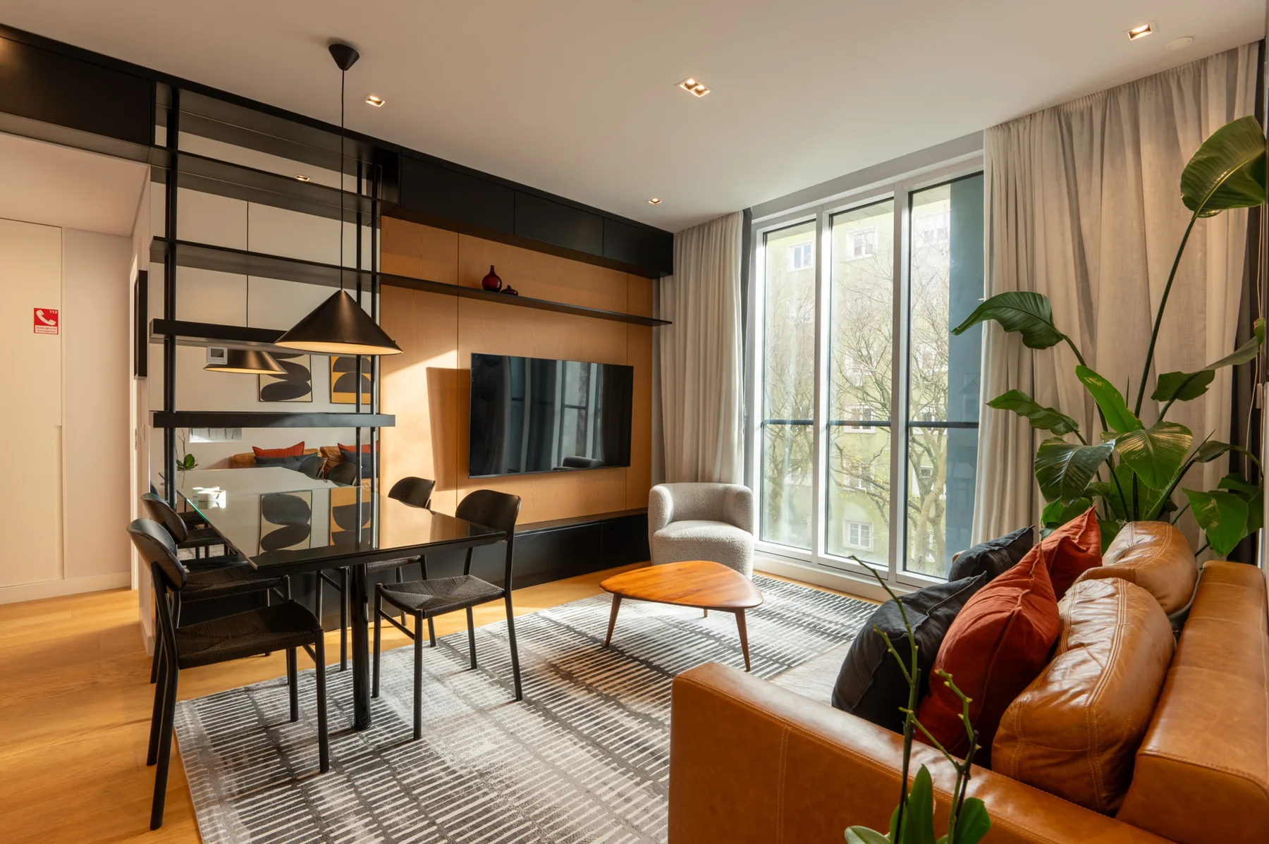 Living and dining area with a television, table, seating, and large windows.
