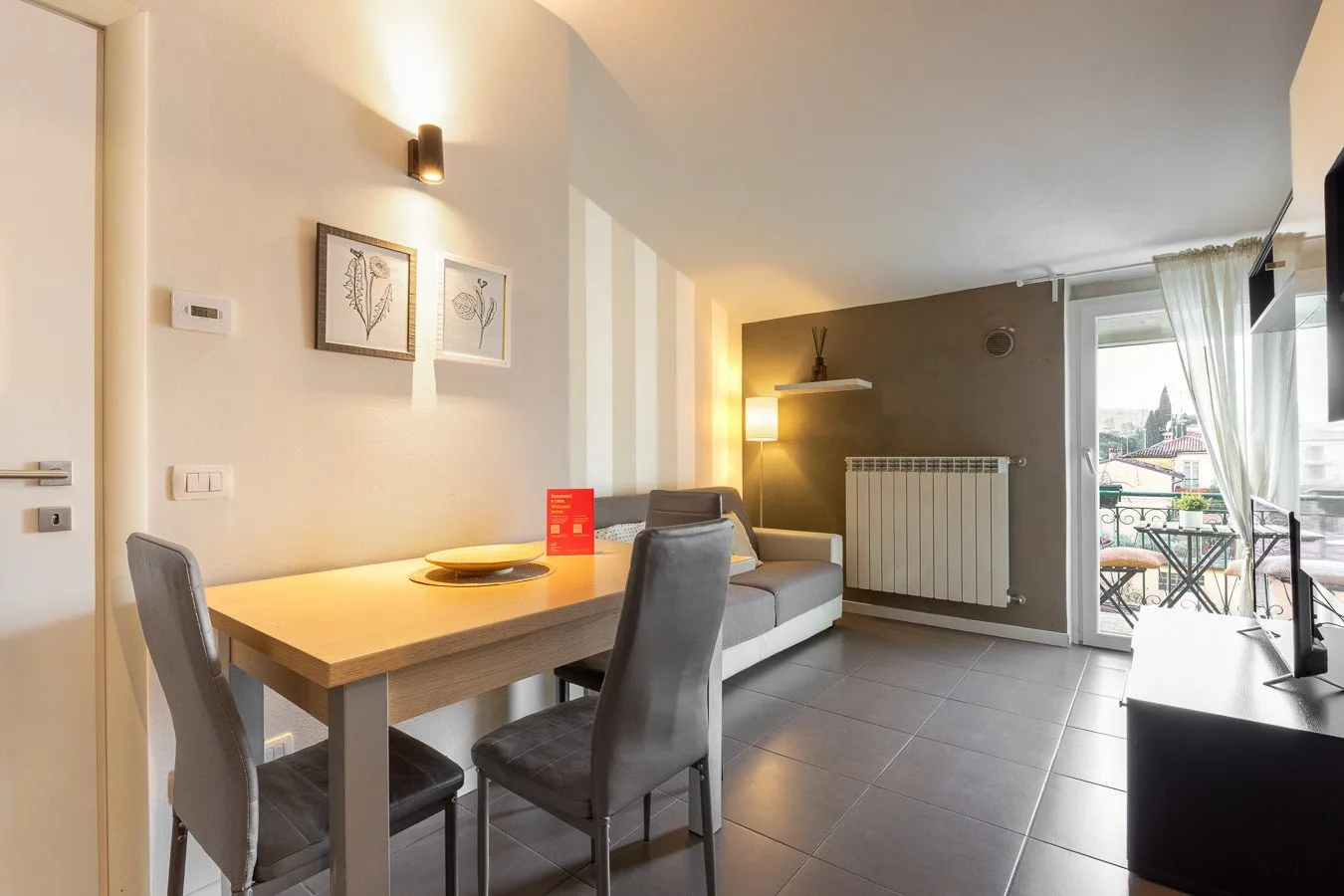 Zona de comedor y sala con mesa, asientos y una luminosa puerta al balcón.