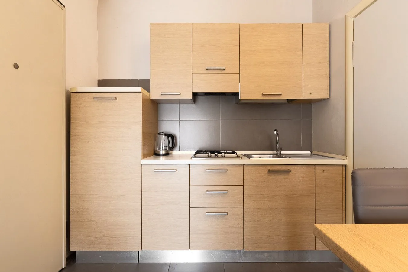 Una cocina compacta con gabinetes de madera clara, una estufa y un fregadero.