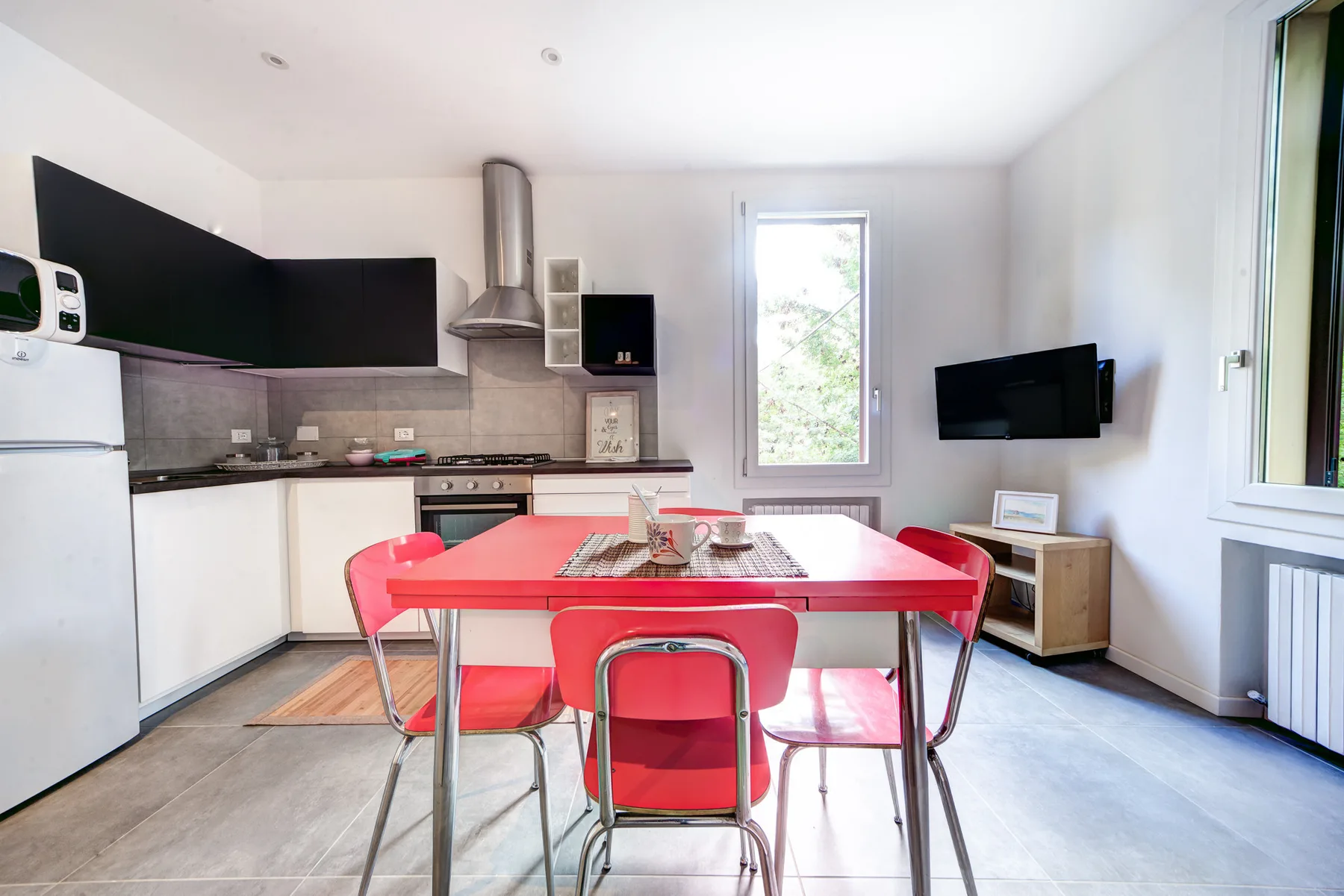 Una cocina y comedor luminosos con una mesa roja y sillas.