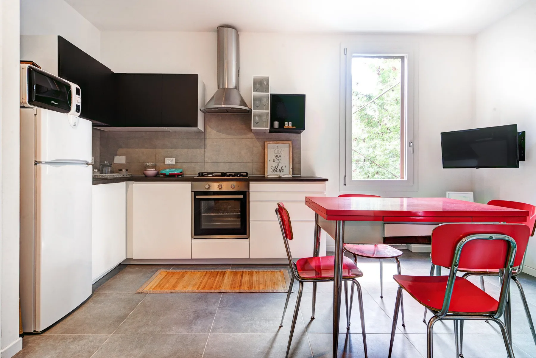 Una cocina y comedor con asientos rojos y un televisor montado en la pared.