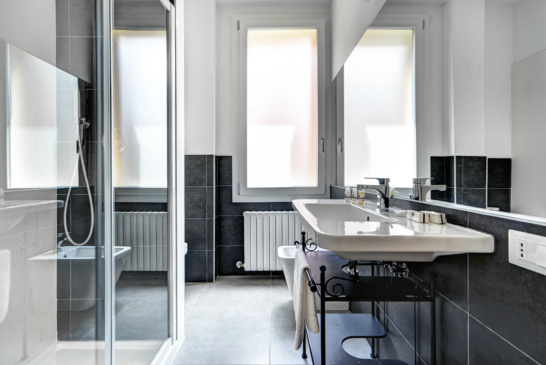 Un baño luminoso con ducha de vidrio, lavabo y ventanas.