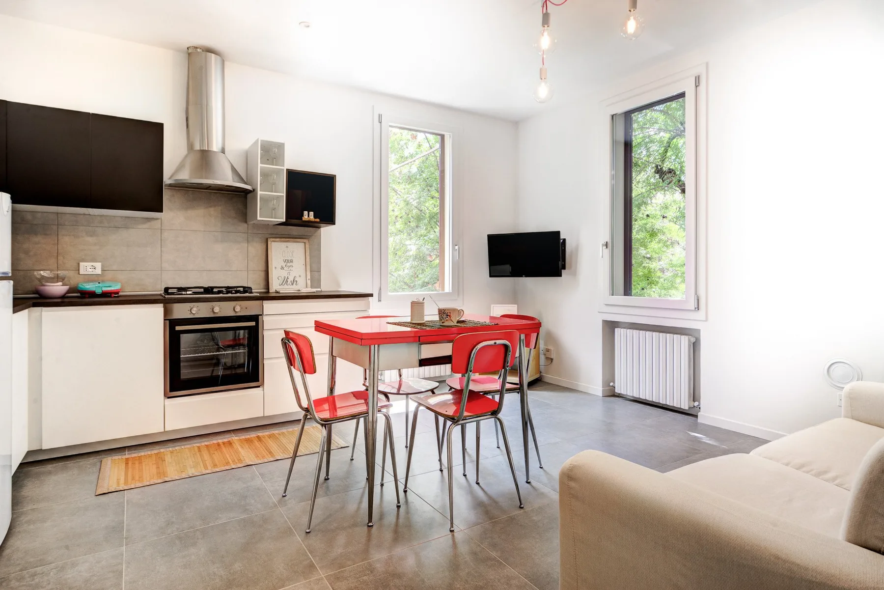 Una cocina abierta y luminosa con una mesa roja y sillas.
