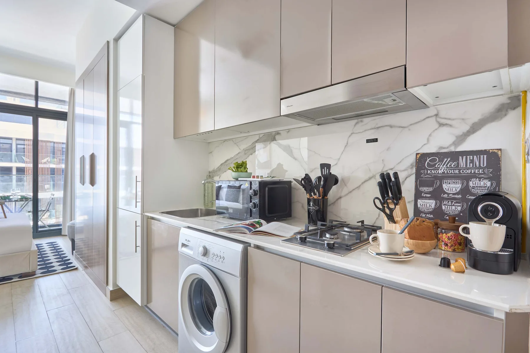 A modern kitchen with a cooktop, countertop appliances, and tall cabinets.