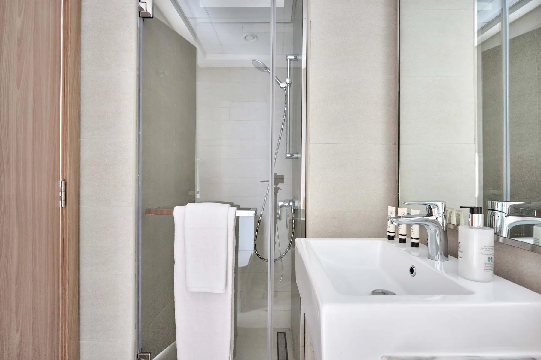 Un baño moderno con una ducha de vidrio y un lavabo blanco.