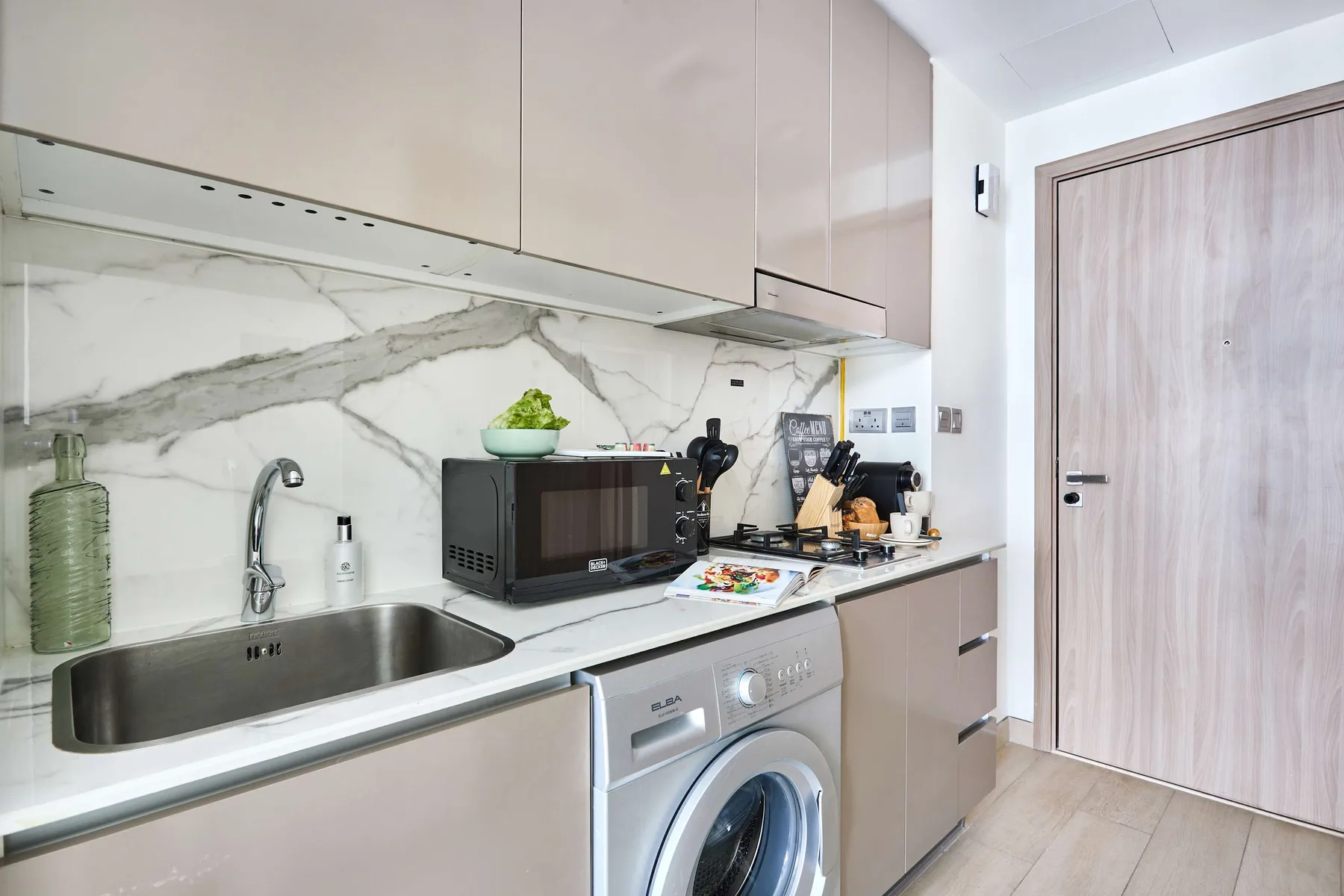 Una cocina compacta con electrodomésticos sobre la encimera y una lavadora debajo.