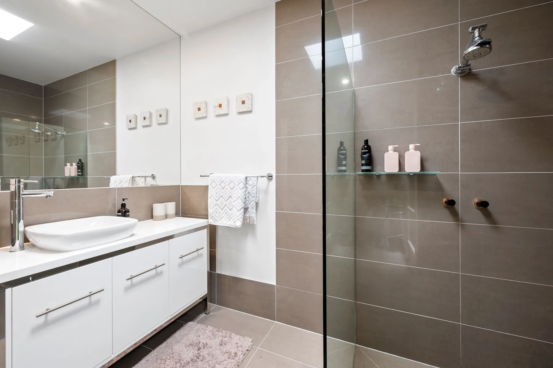 Un baño moderno con lavabo y ducha alicatada.