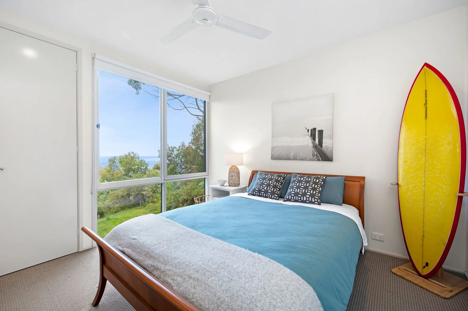 Un dormitorio con una cama junto a una ventana grande con vistas a la vegetación.
