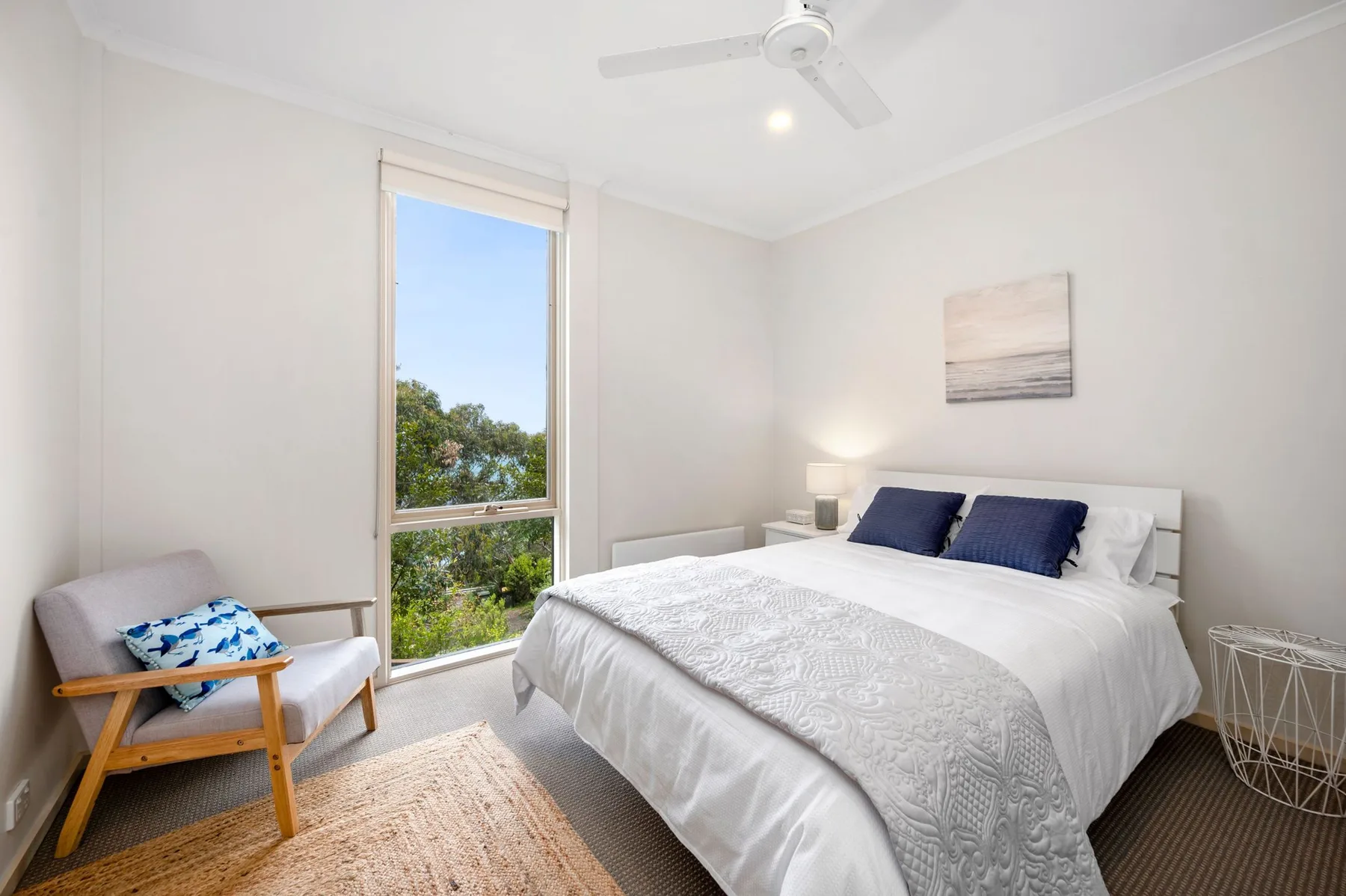 Un dormitorio luminoso con una cama grande y una ventana con vistas a la vegetación.