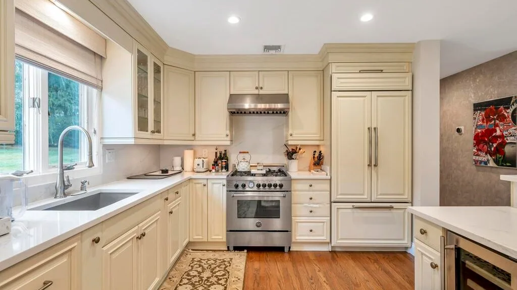 A bright kitchen with cream-colored cabinetry, countertops, and a stainless steel range.