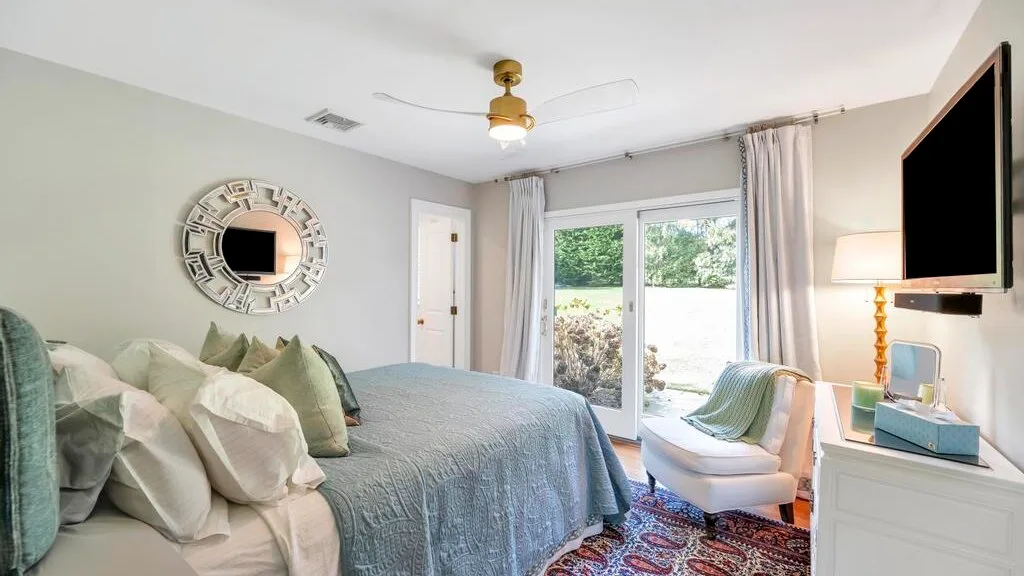 A bedroom with a bed, a wall-mounted television, and glass doors opening to a patio.