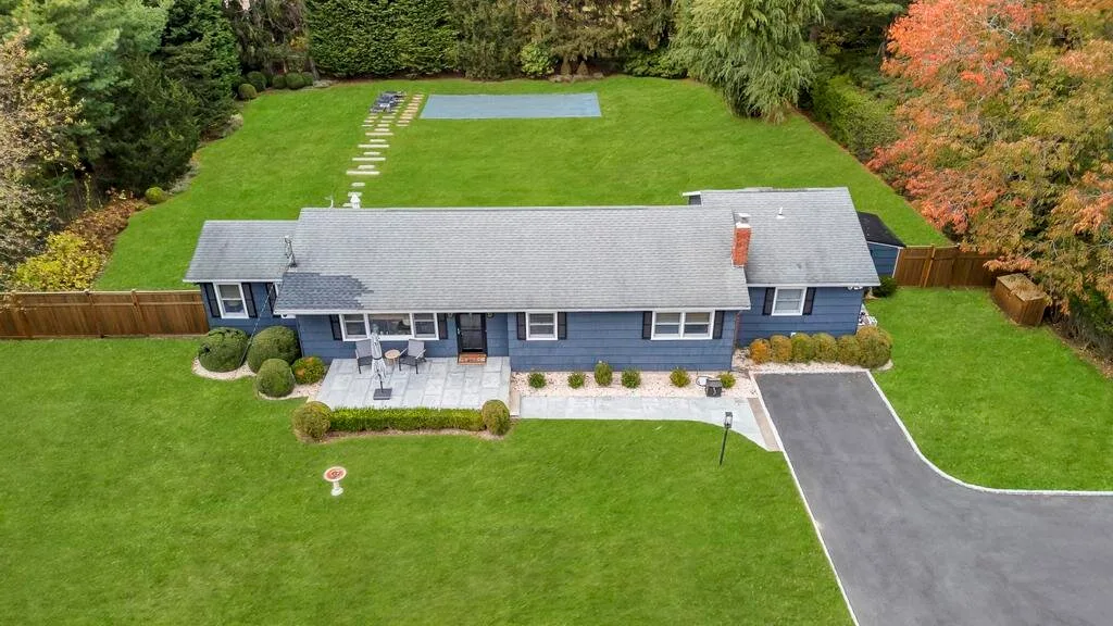 Aerial view of a house with a broad green lawn and trees.