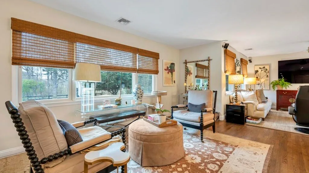 A bright living room with seating arranged around a coffee table and large windows.