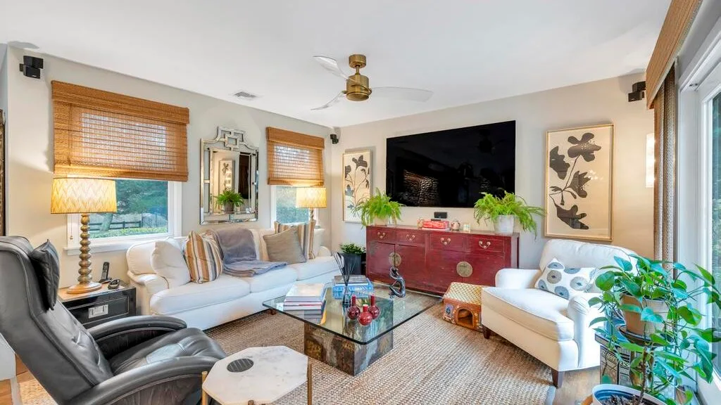 A living room with seating arranged around a glass coffee table and television.