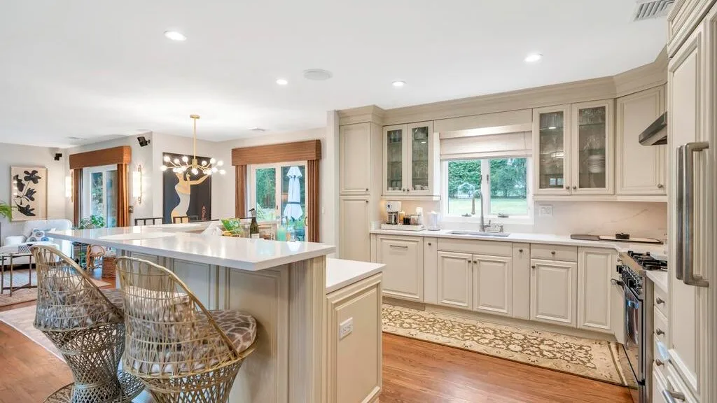A bright kitchen with a large island, cabinetry, and a dining area.